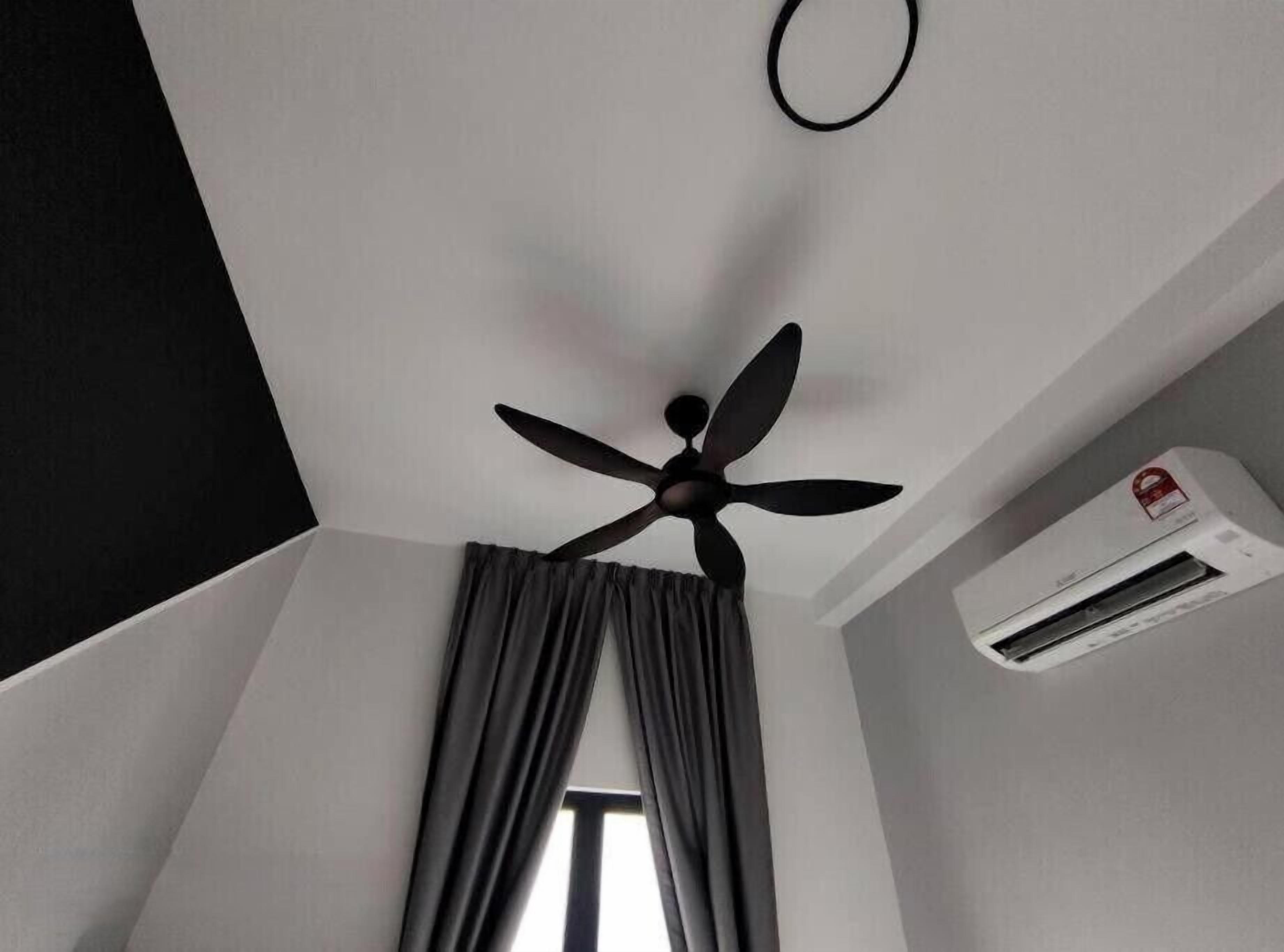 Un ventilador de techo, una ventana con cortinas y un equipo de aire acondicionado en una habitación.
