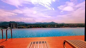 An infinity pool with a view of mountains and a cityscape.