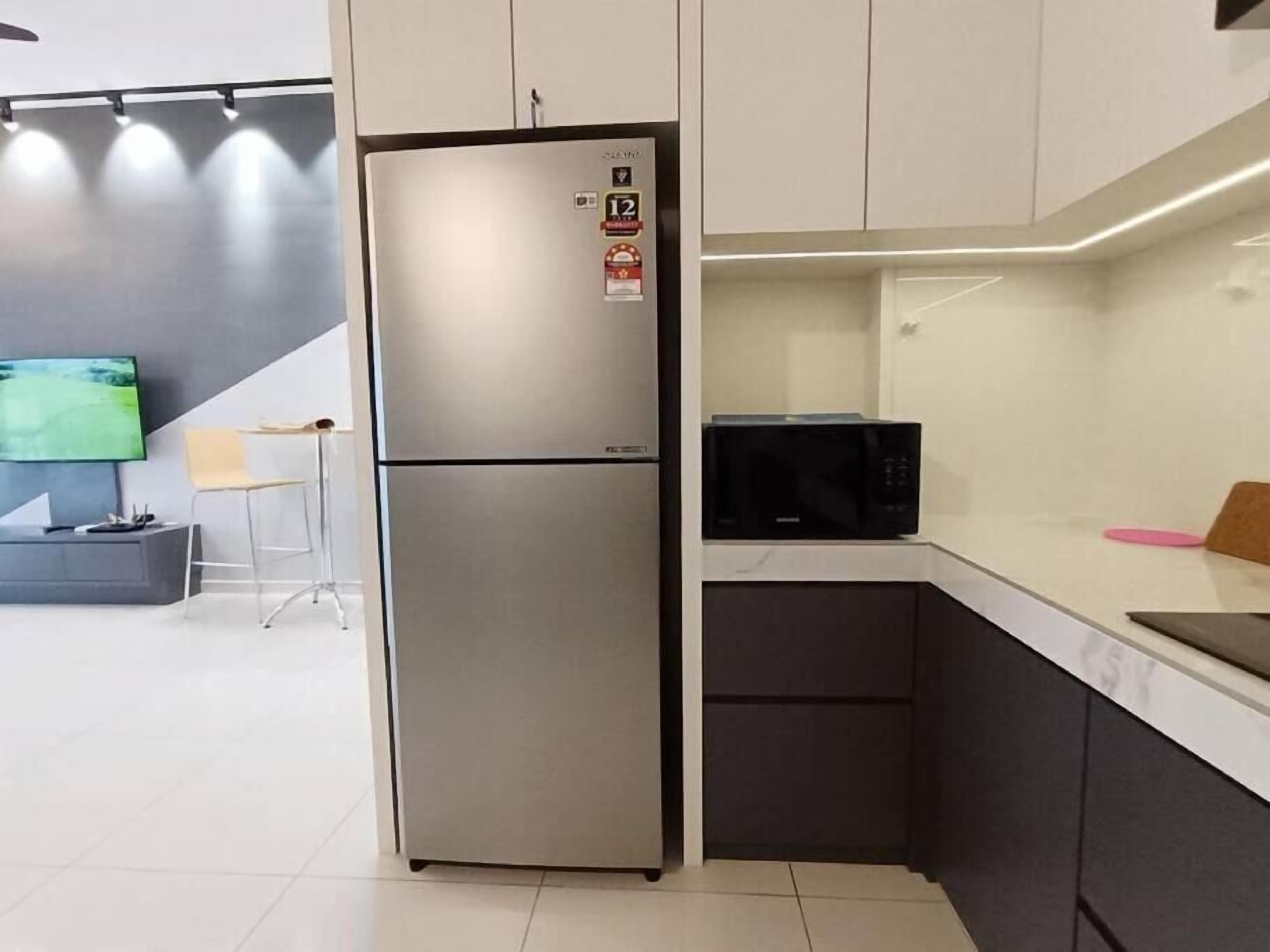 Een kleine keuken met een roestvrijstalen koelkast, een magnetron en een klein aanrecht.