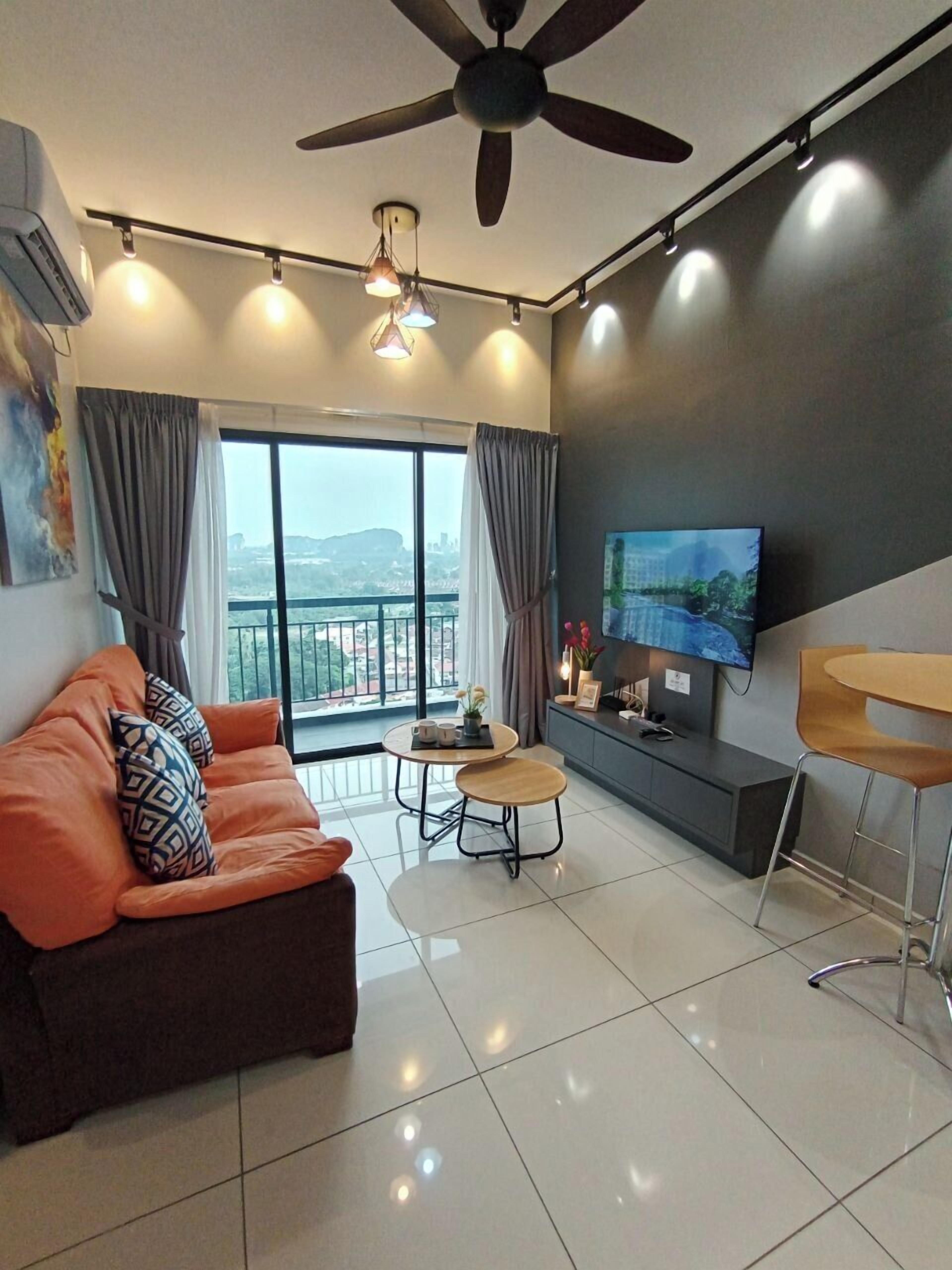 A modern living room with a sofa, a small round table, a TV, and a balcony view.