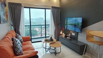 A modern living room with a sofa, a small round table, a TV, and a balcony view.