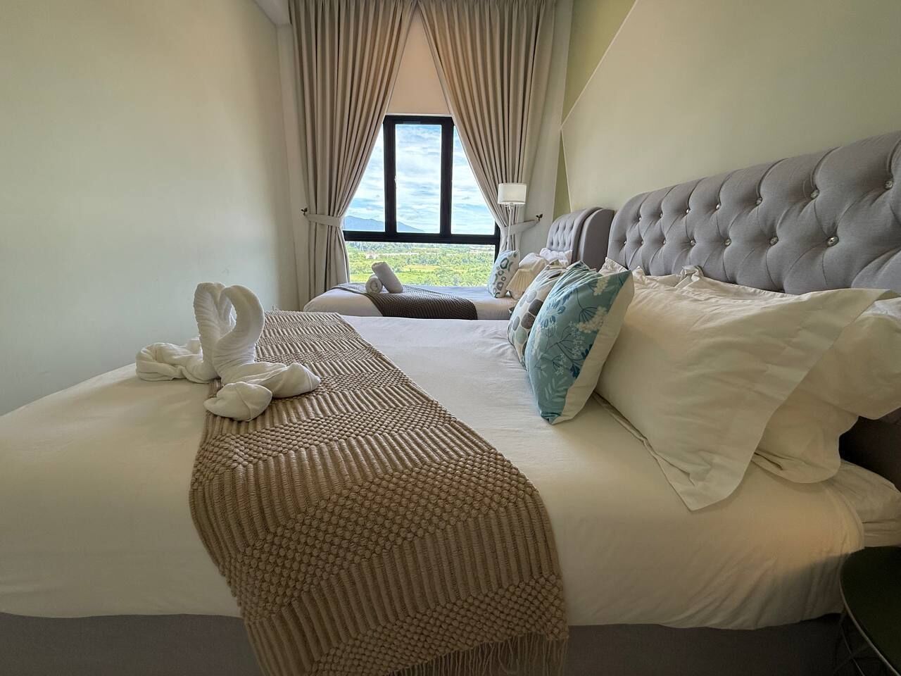 Una habitación de hotel con una cama grande, vistas al exterior y una ventana con cortinas.