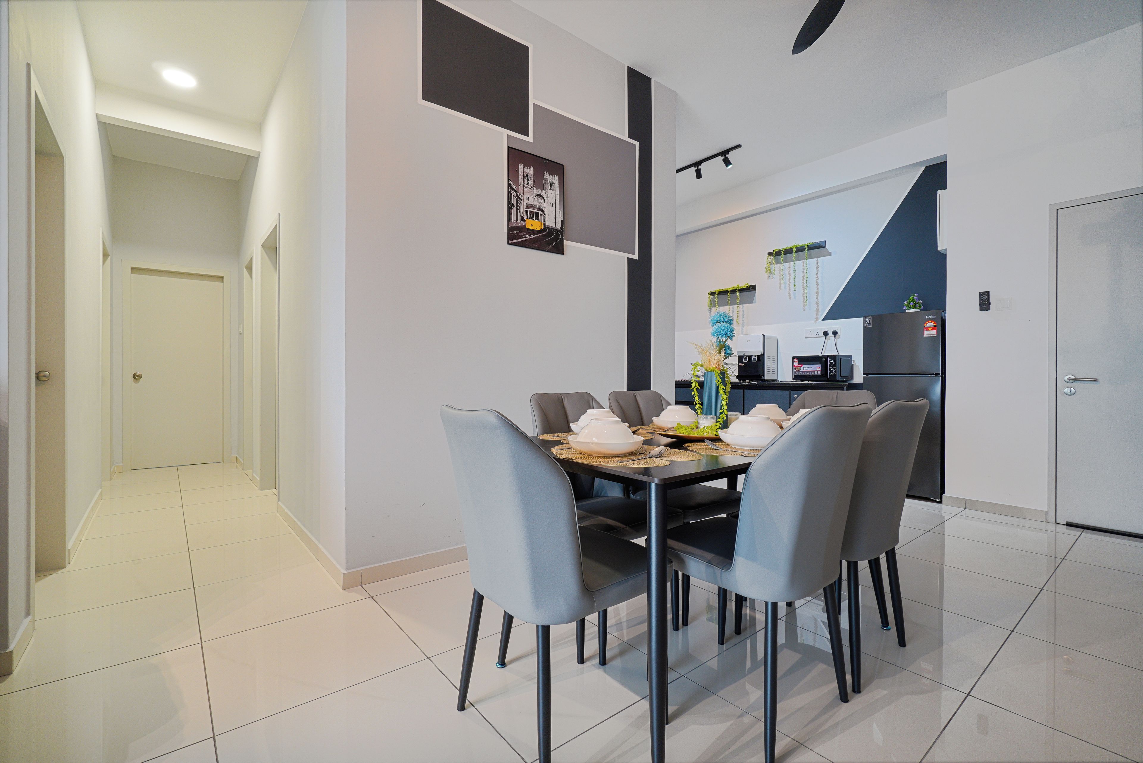 Un espace repas moderne avec une table rectangulaire, six chaises et une cuisine en arrière-plan.