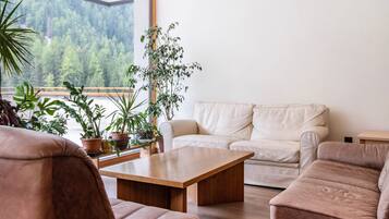 Un soggiorno moderno con un divano color beige, un tavolino in legno e diverse piante in vaso.