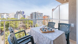A balcony with a table set for tea, chairs, and a view of the cityscape.