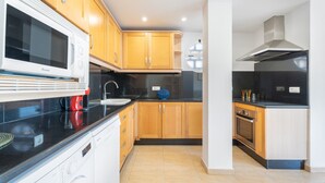 A modern kitchen with wooden cabinets, a black countertop, a built-in oven, and a dishwasher.