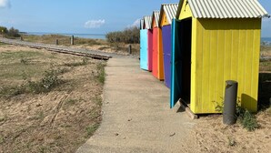 A row of colorful beach huts with a sandy path leading to them. - Room with Private Bathroom near the Beaches of Oléron Island (Le Château-d'Oléron)