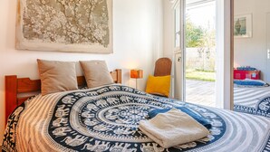 A bedroom with a large bed, a painting, a lamp, and a view of the outdoors. - Room with Private Bathroom near the Beaches of Oléron Island (Le Château-d'Oléron)