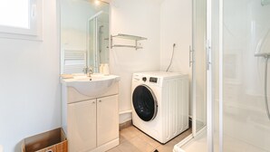 A modern bathroom with a sink, mirror, washing machine, and shower. - Room with Private Bathroom near the Beaches of Oléron Island (Le Château-d'Oléron)