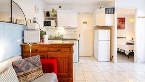 Een compacte keuken met witte kastjes, een magnetron, een koelkast en een houten kookeiland.