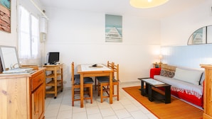 Een kamer met een houten eettafel, stoelen, een bank, een televisie en een lamp.