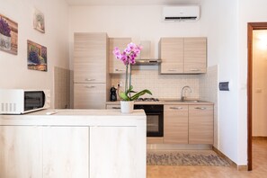 A modern kitchen with wooden cabinets, a microwave, a sink, and a potted orchid.