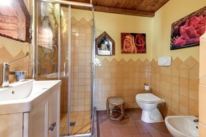 Une salle de bain équipée d’une douche, de toilettes, d’un bidet et d’un lavabo.
