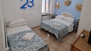 Habitación con dos camas, el número 23 en la pared, una ventana con cortinas y un ventilador de techo.