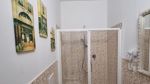 Un baño con ducha, inodoro y lavamanos. Hay tres cuadros colgados en la pared.