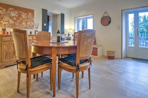 Un coin repas avec une table et des chaises en bois, une bouteille de vin et un tableau accroché au mur.