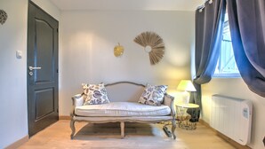 A room with a sofa, a lamp, a radiator, and a window with curtains.