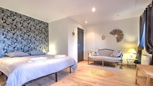A bedroom with a bed, a bench, a lamp, and a wall with a textured pattern.