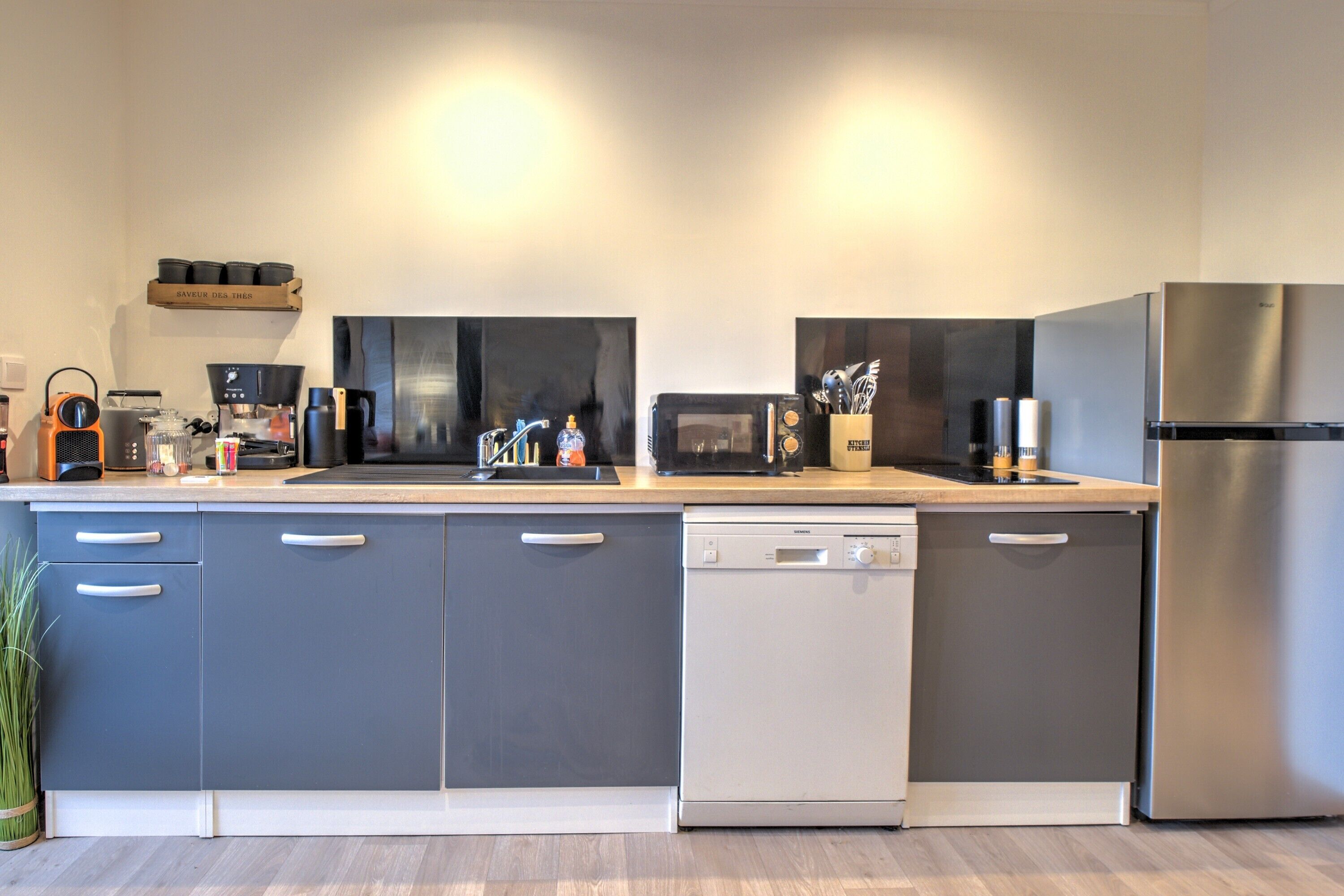 Una cocina moderna con lavavajillas, microondas y refrigerador de acero inoxidable.