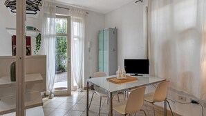 Ein modernes Zimmer mit Esstisch, Stühlen, Fernseher und Schrank.