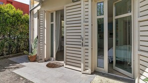 Ein Haus mit Schiebetür, einem Blumentopf mit Kaktee und einer gefliesten Terrasse.