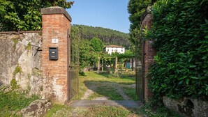 Un portail rustique mène à un bâtiment blanc entouré de verdure.