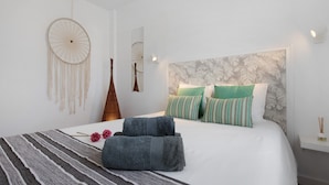 A neatly made bed with a striped blanket, two pillows, a dreamcatcher, and a mirror on the wall. - Vacation Home 'Casa Alisios' with Mountain View, Private Terrace and Wi-Fi (Costa Calma)
