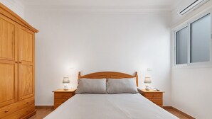 Een slaapkamer met een houten bed, twee nachtkastjes met lampen, een kledingkast en een raam.