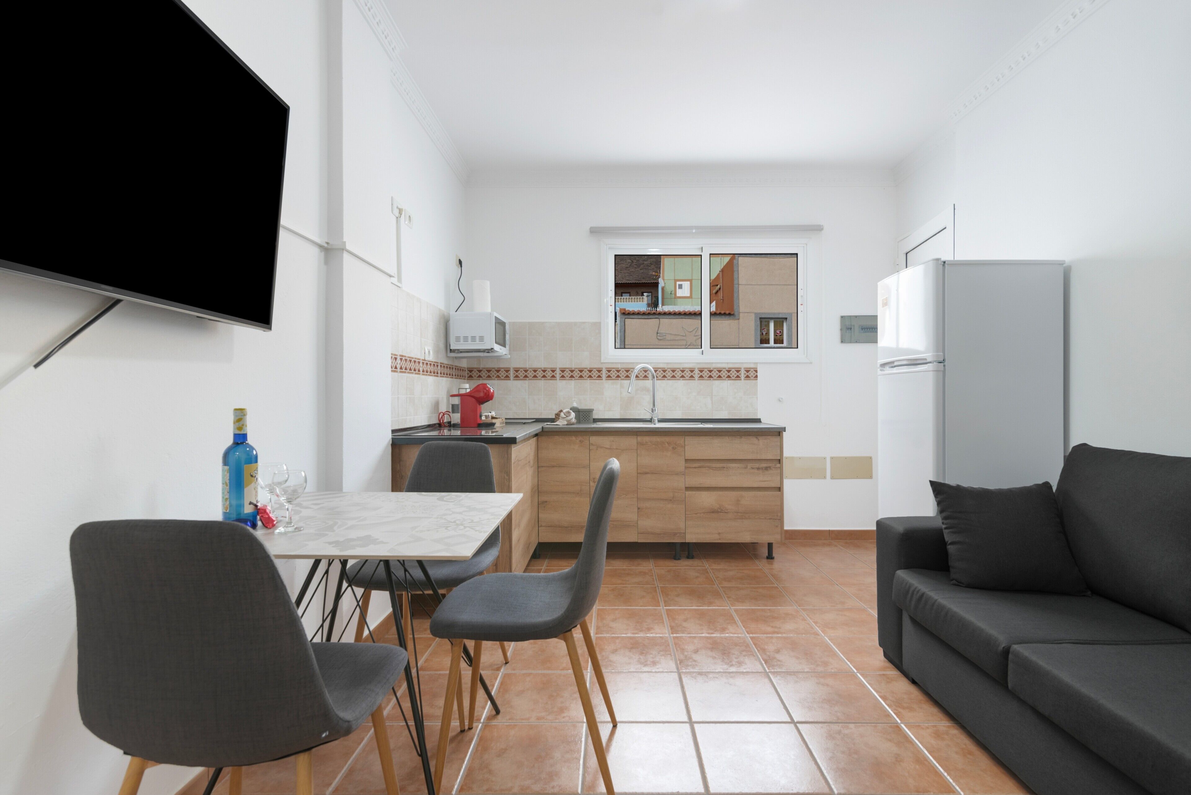 Una cocina compacta con comedor, televisión de pantalla plana y refrigerador.