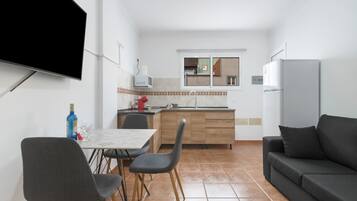 Una cocina compacta con comedor, televisión de pantalla plana y refrigerador.
