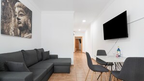 Una sala moderna con un sofá modular, un televisor de pantalla plana y un comedor con sillas y una mesa.