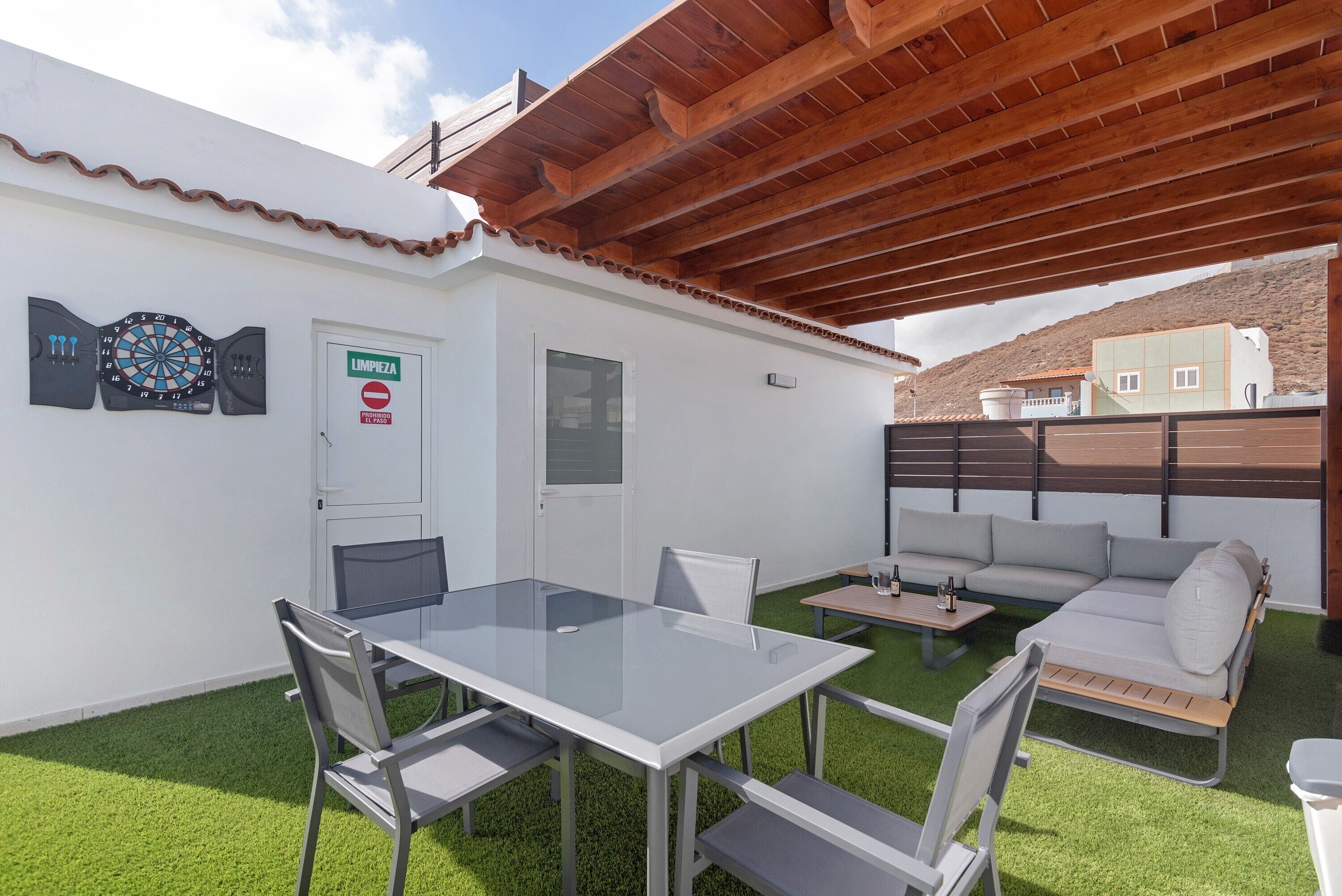 Un patio con una mesa, sillas, un sofá y un dardo.