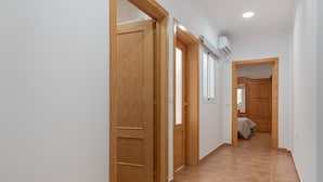 Un pasillo con puertas de madera, piso de baldosas y un equipo de aire acondicionado.