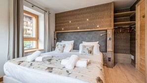 Makuuhuone, jossa on suuri sänky, puinen pääty ja näkymä parvekkeelle.