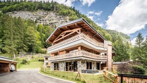 Un edificio de estilo chalet con fachada de piedra, balcones de madera y un paisaje montañoso al fondo.