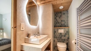 Un baño moderno con tocador de madera, un espejo grande y un salpicadero de azulejos hexagonales.
