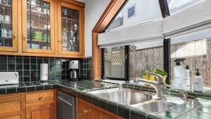 Una cocina con armarios de madera, lavavajillas, cafetera y un lavabo con grifo.