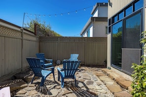 A patio area with blue chairs, a stone pathway, and a wooden fence.