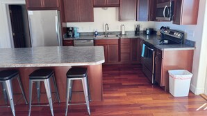 A kitchen with wooden cabinets, a stainless steel refrigerator, a dishwasher, a microwave, a stove, and a trash can. - Spacious 6-bedroom+ Studio Apartment with 12+ Guests-Dog friendly in Homer Hills (Homer)