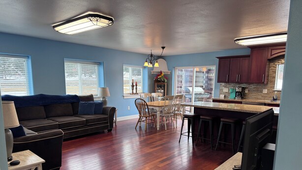 A modern living room with a sofa, dining table, and kitchen area with wooden flooring and cabinets. - Spacious 6-bedroom+ Studio Apartment with 12+ Guests-Dog friendly in Homer Hills (Homer)