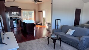 A modern living space with a kitchen, dining area, and a gray sofa. - Spacious 6-bedroom+ Studio Apartment with 12+ Guests-Dog friendly in Homer Hills (Homer)