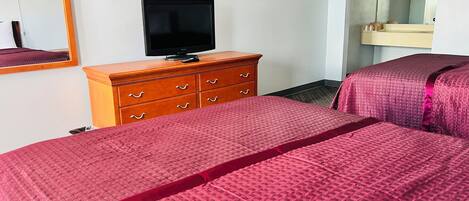 Habitación de hotel con una cama, un aparador de madera, un televisor y un espejo.