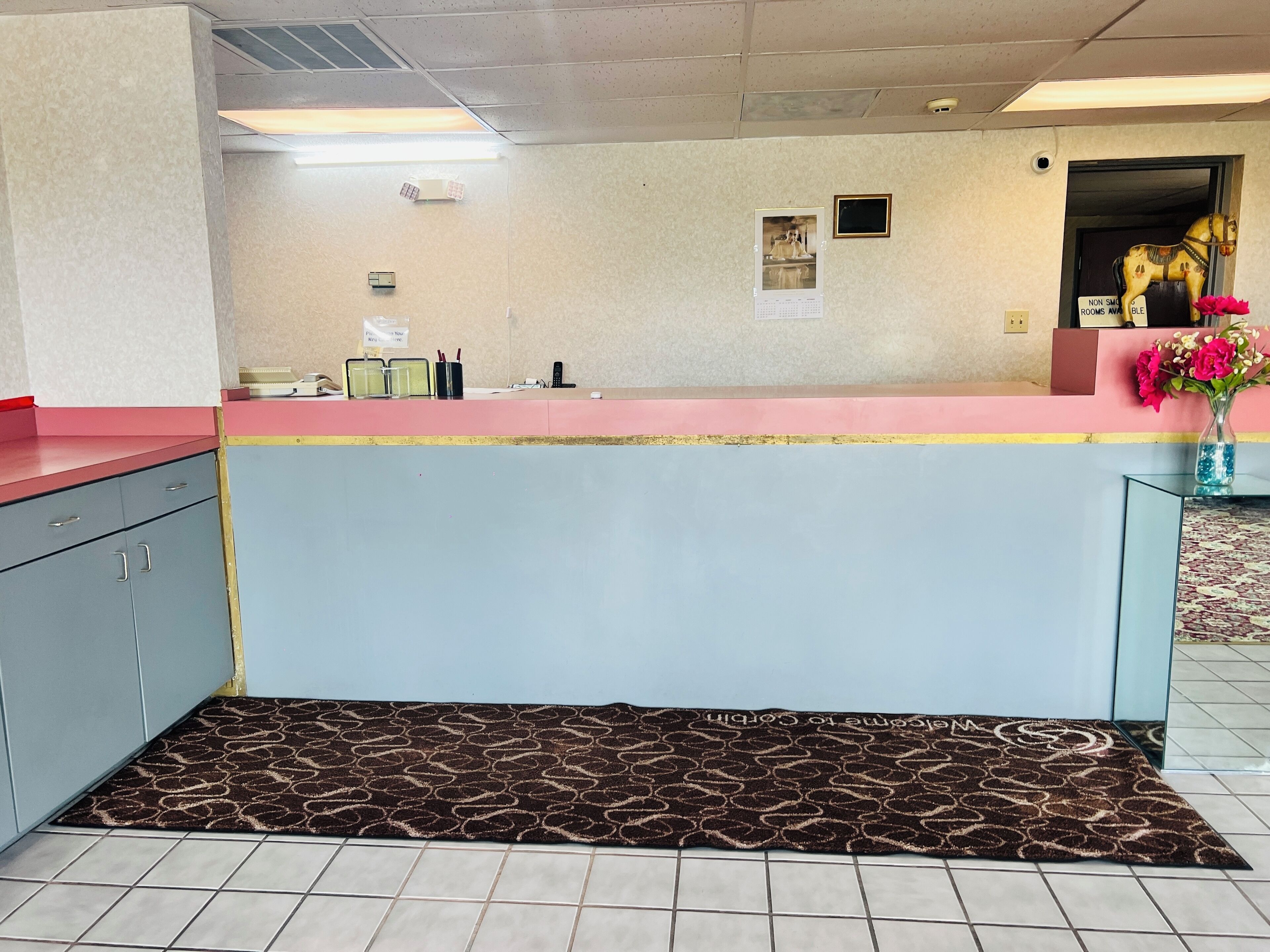 A reception area with a counter, a calendar, a phone, and a sign indicating non-smoking rooms.
