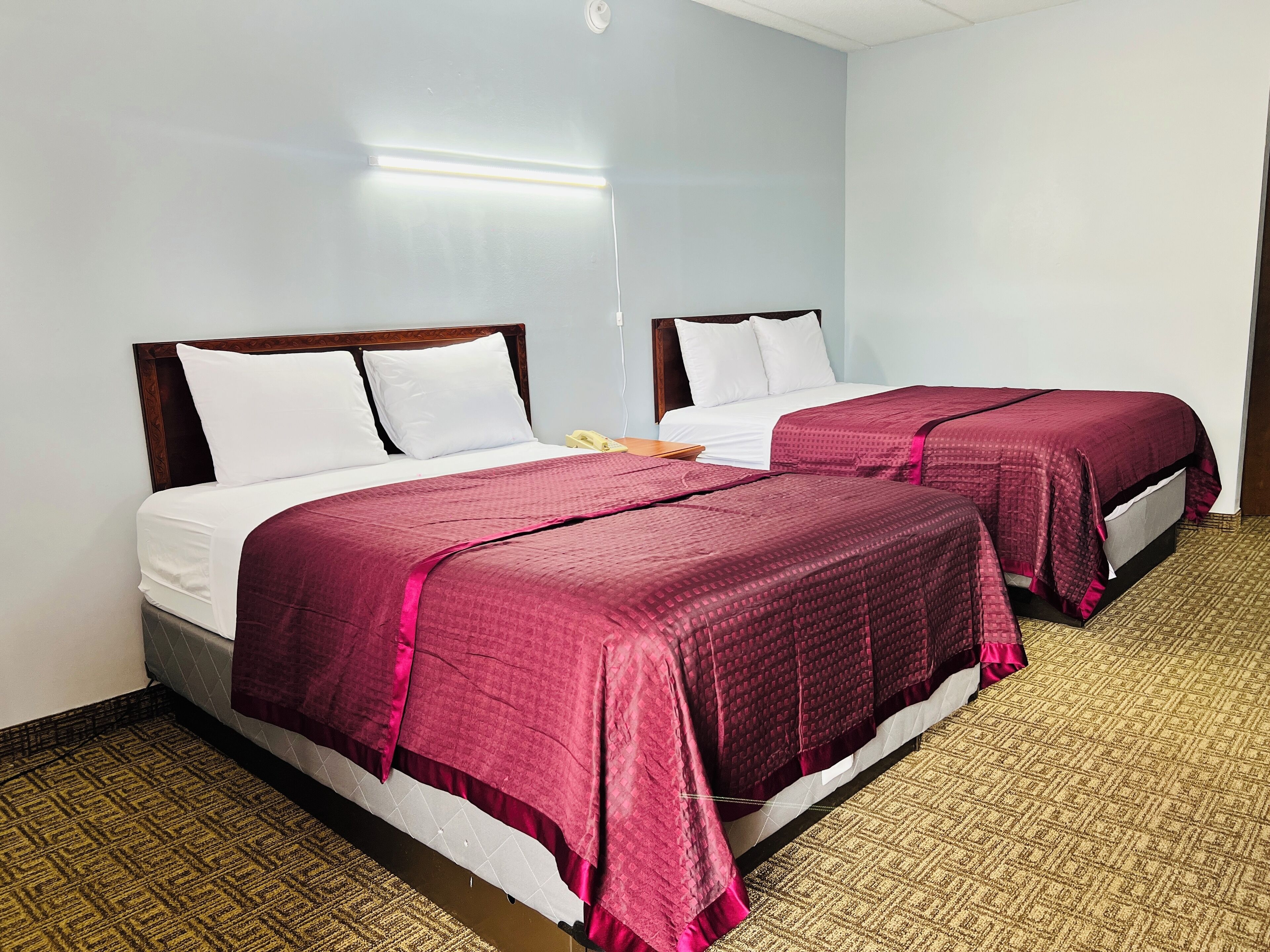 Two single beds with wooden headboards, white bedding, and maroon blankets.