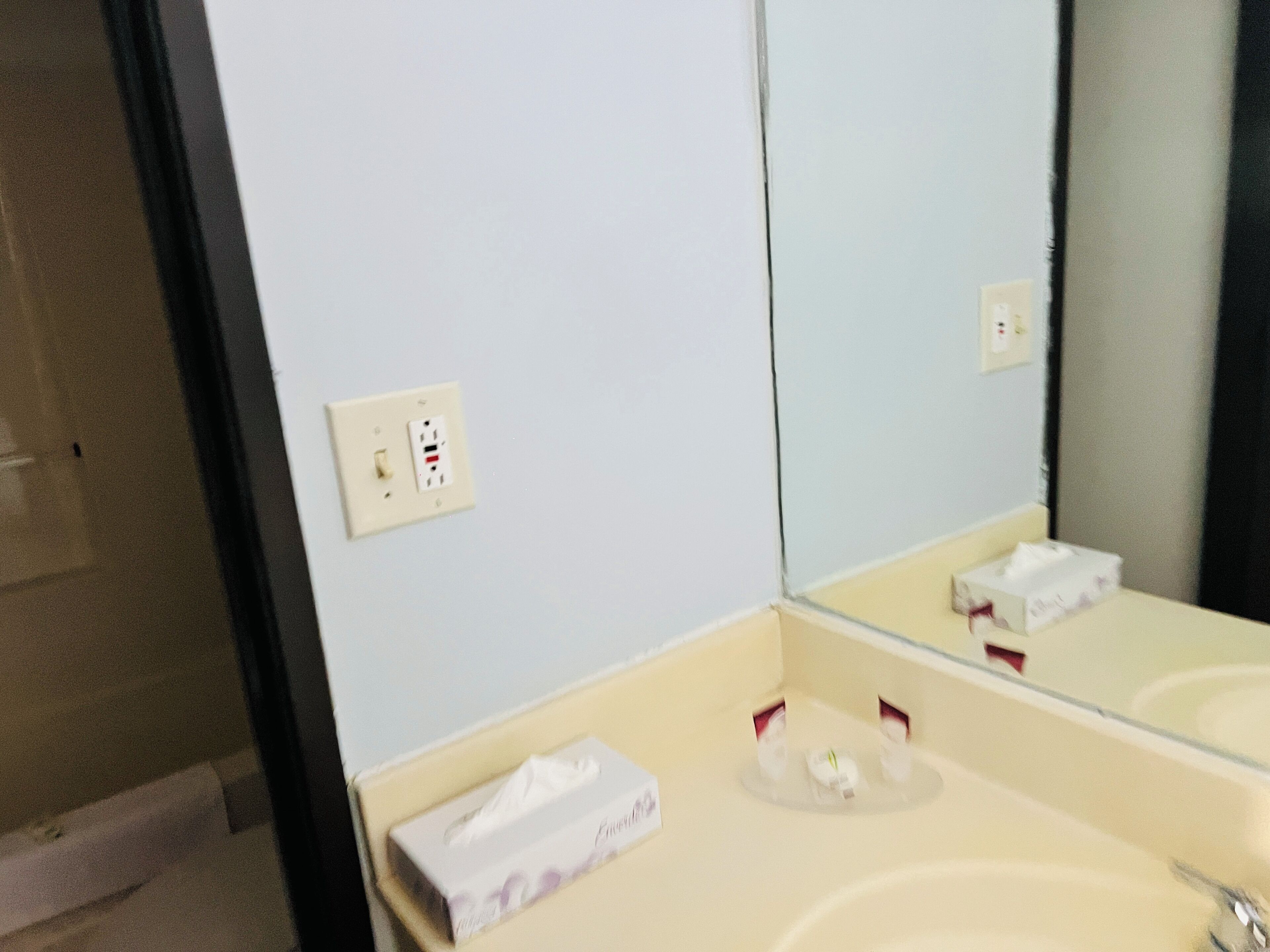 Une salle de bain avec un lavabo blanc, un miroir et un distributeur de serviettes.