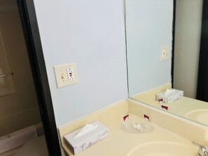 A bathroom with a white sink, a mirror, and a towel dispenser. - Value Stay (Winchester)