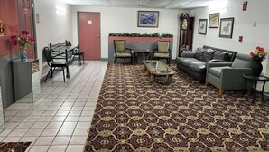 Un hall d’entrée avec un tapis à motifs, un espace détente comprenant des chaises et un canapé, une petite table et un comptoir d’accueil.