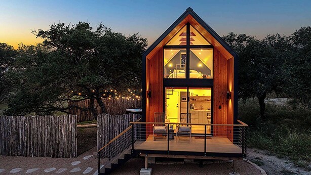 A modern wooden cabin with a glass front, a deck, and a fenced yard. - The Live Oak at Meridian, Hot tub & Firepit! (Fredericksburg)
