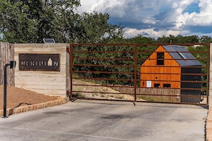 A gated entrance with a sign reading 'MERIDIAN,' a wooden barn with a sloped roof, and a metal gate.