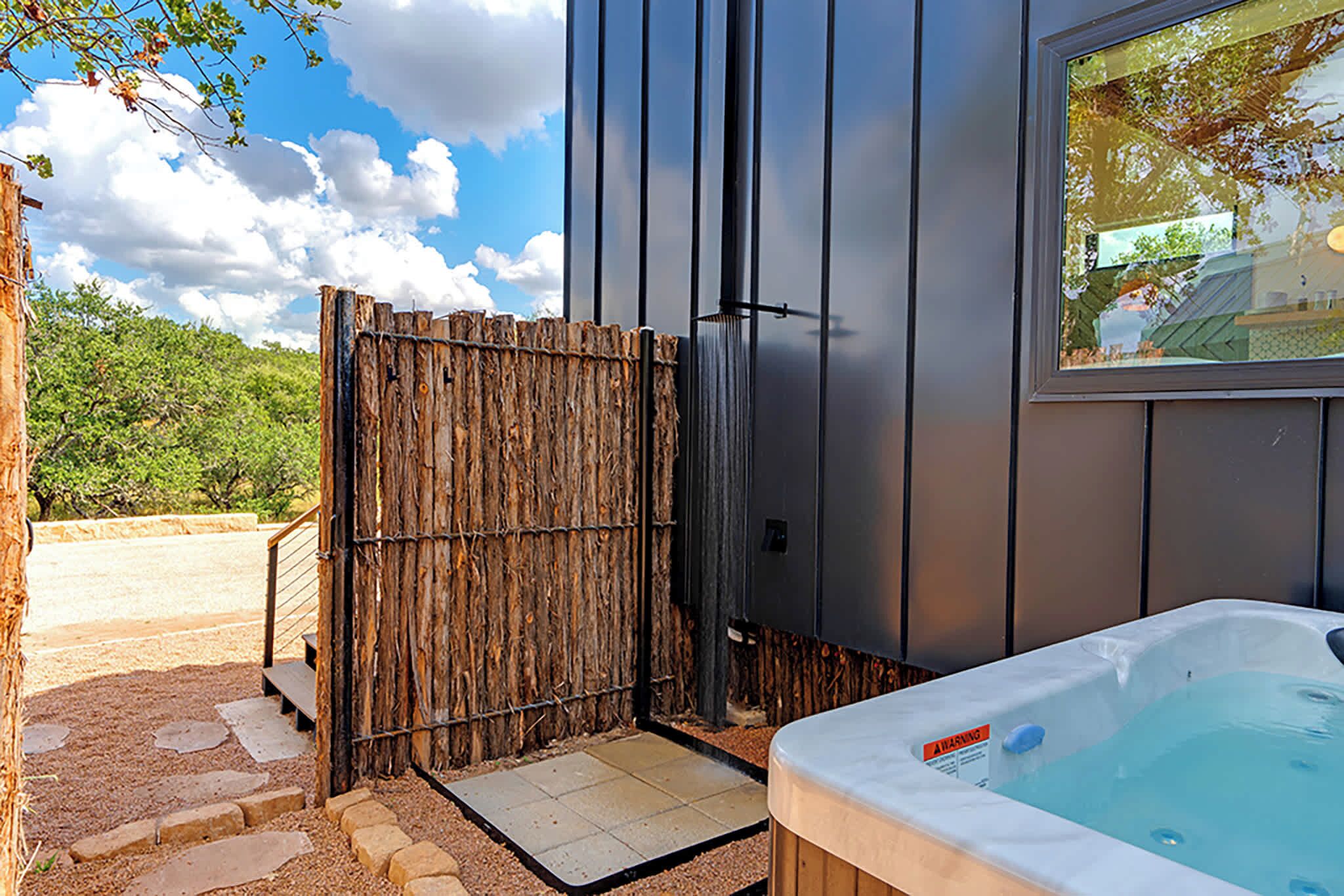 Un área de spa con un jacuzzi, una valla de madera y vistas al exterior.